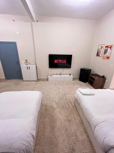 two beds in a room with a tv on the wall at Zamalek studio S1 in Cairo