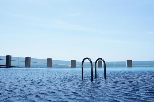 two metal poles in the water with a bridge in the background at Imperio Residence Melaka in Melaka