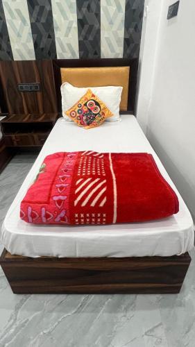 a bed with a red blanket on top of it at Kanak Bihari Yatri Niwas, 100 Meter Ram Ki Paidi, Saryu River in Ayodhya