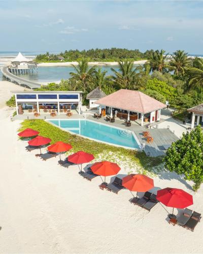 an aerial view of a resort with a pool and red umbrellas at Cinnamon Hakuraa Huraa Maldives - All Inclusive in Meemu Atoll