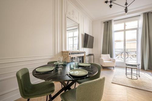 une salle à manger avec une table et des chaises noires dans l'établissement Appartement dauphine muette trocadero - Paris 16 - 4P, à Paris