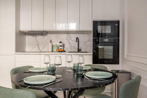 une cuisine avec une table noire et des verres à vin dans l'établissement Appartement dauphine muette trocadero - Paris 16 - 4P, à Paris