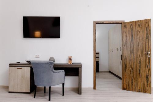 a desk with a chair and a television on a wall at INFINITY PLAZA BLOCK 1 in Atyraū