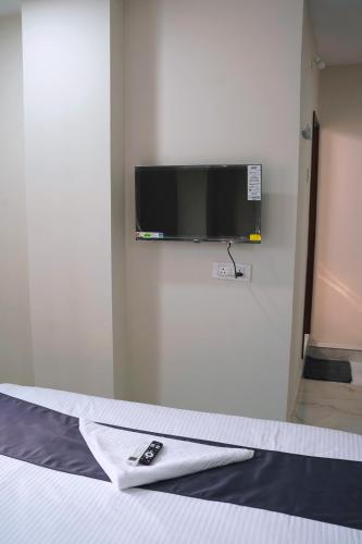 a tv on a wall with a remote control on a bed at RS hotels in Hyderabad