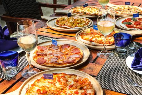 a table with many pizzas on it with glasses of wine at Homm Chura Samui in Chaweng