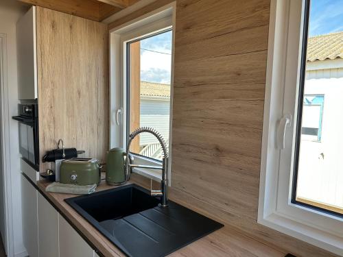 une cuisine avec un évier et une fenêtre dans l'établissement Chalet Linoli, à Gruissan