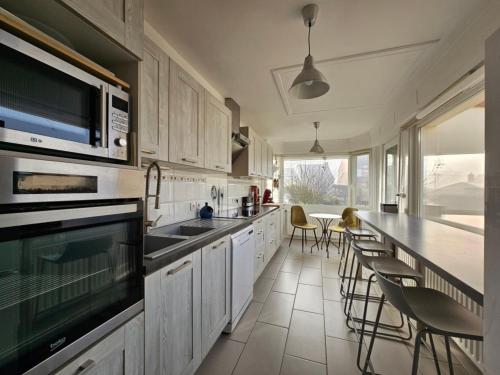 une cuisine avec des placards blancs et un comptoir avec des chaises dans l'établissement Maison familiale de vacances, à Bray-Dunes