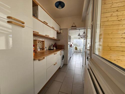 une cuisine avec des armoires blanches et un sol carrelé dans l'établissement Maison familiale de vacances, à Bray-Dunes