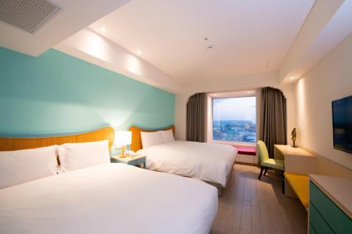 a hotel room with two beds and a window at Kenting Long Beach Hotel in Checheng