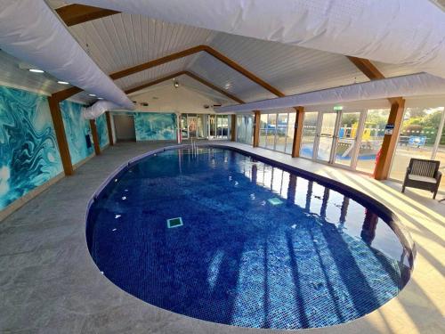 a large swimming pool with blue water in a building at Golden Dunes Retreat, Dog-Friendly Stay at Par Sands Holiday Park, Cornwall in Par