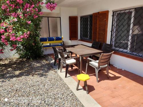 een houten tafel en stoelen op een patio met bloemen bij Casa Límon in Torredembarra