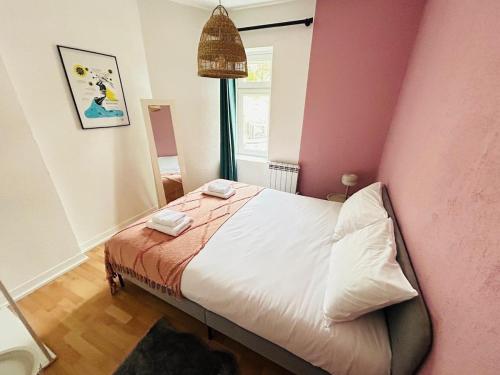 une chambre avec un lit et un mur rose dans l'établissement Appartement rénové quartier historique, à Caen