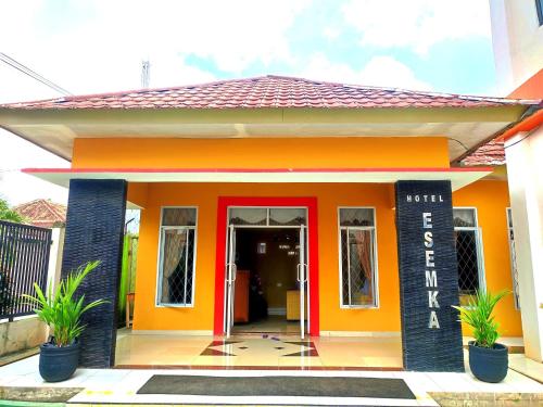 a small orange building with a red door at Esemka Hotel and Convention Kotabumi in Kotabumi