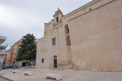 ein großes Backsteingebäude mit Bänken davor in der Unterkunft Sognare in Puglia in Valenzano