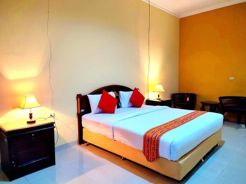 a bedroom with a large bed with red pillows at Esemka Hotel and Convention Kotabumi in Kotabumi