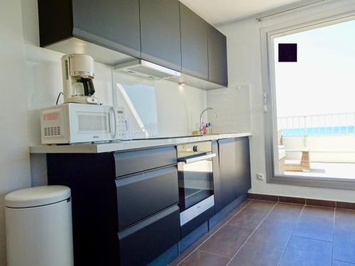 La cuisine est équipée d'un four micro-ondes et d'un évier. dans l'établissement PGH N5-25m de la plage, Vue Mer, Piscine, Parking, à La Grande Motte