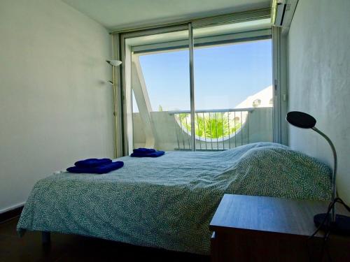 une chambre avec un lit et une grande fenêtre dans l'établissement PGH N5-25m de la plage, Vue Mer, Piscine, Parking, à La Grande Motte