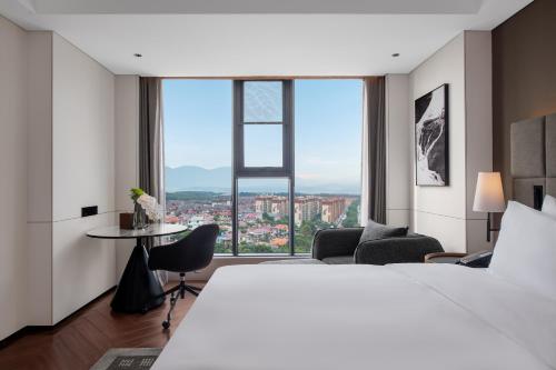 a hotel room with a bed and a large window at Intercity Jinghong Xishuangbanna in Jinghong
