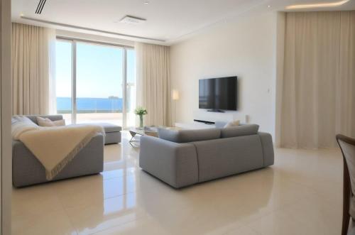 a living room with two couches and a flat screen tv at Beachfront Luxury Villa Glory in Ayia Napa