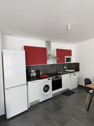 une cuisine avec des appareils électroménagers blancs et des armoires rouges dans l'établissement Appartement paisible et spacieux, à Jonzac