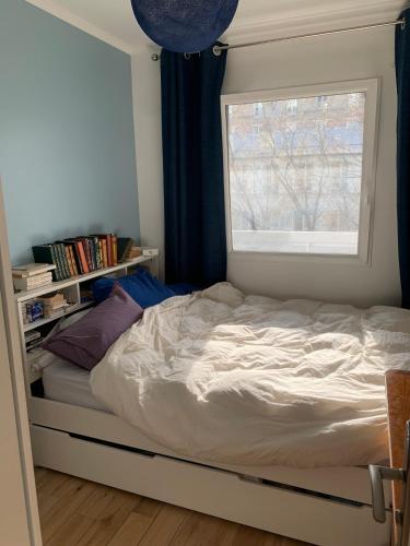 un lit dans une chambre avec une fenêtre dans l'établissement Sunny escape in Belleville, à Paris