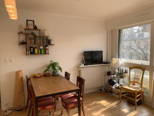 une salle à manger avec une table, des chaises et une télévision dans l'établissement Sunny escape in Belleville, à Paris