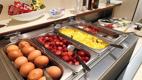 a buffet with eggs eggs potatoes and strawberries in trays at Hotel President in Prato