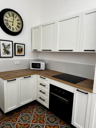 a kitchen with white cabinets and a clock on the wall at Stylish Boutique Duplex Apartment Home - Green - 2 Large Double Bedrooms with Ensuite Bathrooms in Msida