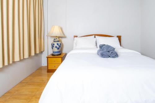 a bedroom with a white bed with a night stand and a lamp at TOM CAFE MY House in Thung Maha Mek