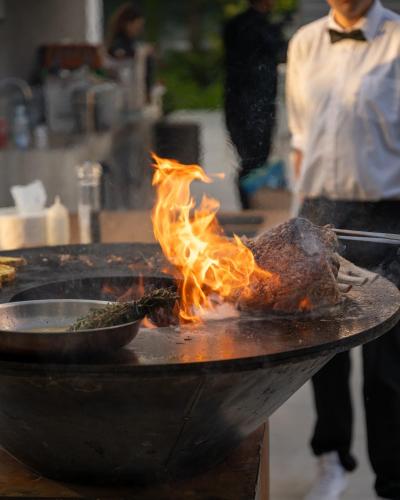 a man is cooking food in a pan with flames at Beachfront Luxury Villa Glory in Ayia Napa