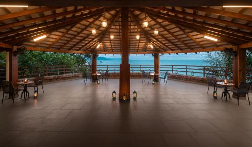 a pavilion with tables and chairs and a view of the ocean at Highland Sarovar Portico Sindhudurg in Bhogwe