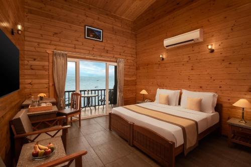 a bedroom with a bed and a balcony with the ocean at Highland Sarovar Portico Sindhudurg in Bhogwe