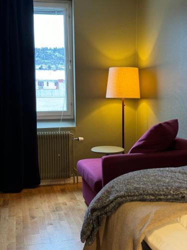 a living room with a purple couch and a window at Strand City Hotel in Örnsköldsvik