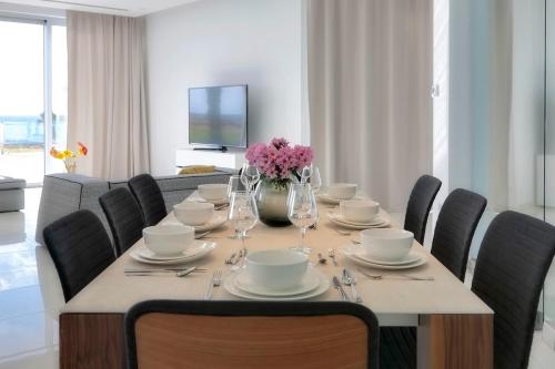 a dining room table with chairs and a vase of flowers at Beachfront Luxury Villa Glory in Ayia Napa