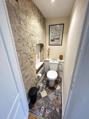 La salle de bains est pourvue de toilettes et d'un mur en pierre. dans l'établissement Superbe loft de charme - centre ancien, à Caen