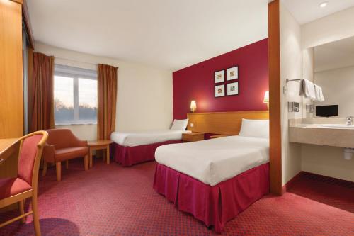 um quarto de hotel com duas camas e um lavatório em Days Inn Stevenage North em Baldock