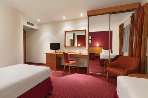 a hotel room with a bed and a desk at Days Inn Stevenage North in Baldock
