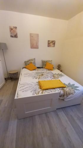 a bed in a room with yellow pillows on it at Rez-de-chaussée Saint Marcel jardin partagé in Laon