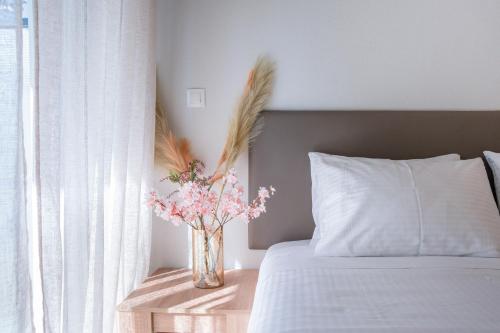 a vase of flowers on a table next to a bed at Sunwaves City Center Apartment in Rhodes Town