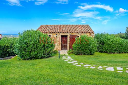 a small brick building with a red door in a yard at Domus de pedra in Marina di Portisco