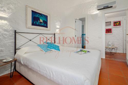 a bedroom with a large white bed in a room at Domus de pedra in Marina di Portisco