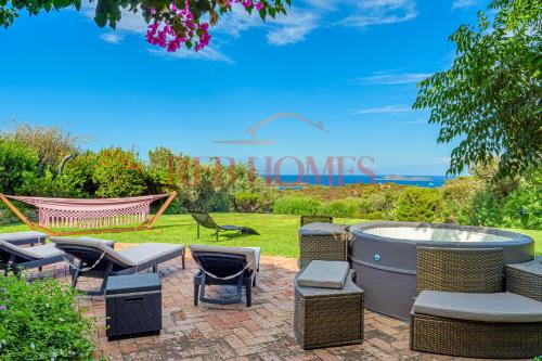 a patio with wicker chairs and a hot tub at Domus de pedra in Marina di Portisco