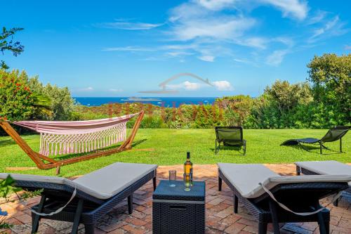 a patio with a hammock and chairs and the ocean at Domus de pedra in Marina di Portisco