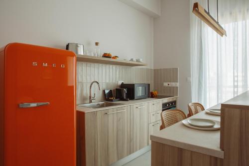 a kitchen with an orange refrigerator in a kitchen at LIV & CO Suites & Villas in Voroklini