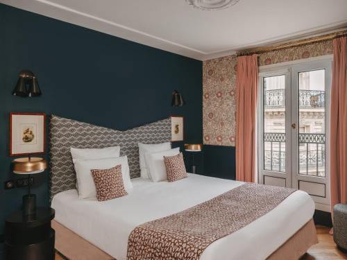 a bedroom with a large white bed and a window at Maison Malesherbes in Paris