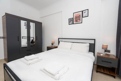 a bedroom with a white bed and a black cabinet at B lackstone Homes in Aksu