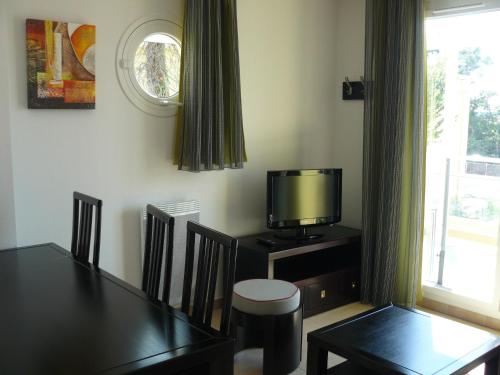 une salle à manger avec une table et une télévision sur une table dans l'établissement Terrasses des Embiez, à Six-Fours-les-Plages