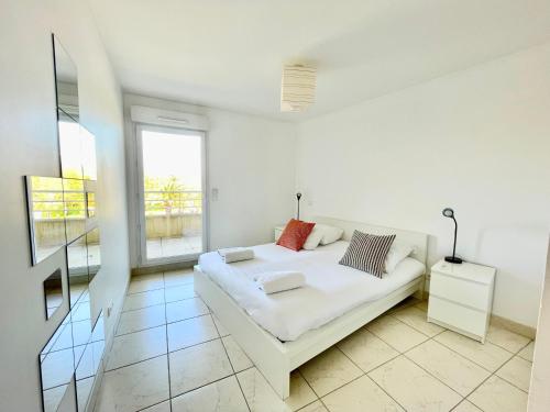 une chambre blanche avec un lit blanc et une fenêtre dans l'établissement PGH N7- 100m de la Plage, Vue Mer & Parking Privé, à La Grande Motte