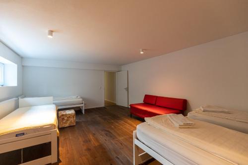 a room with two beds and a red couch at Ferienoase Granula - Bad Ragaz in Bad Ragaz
