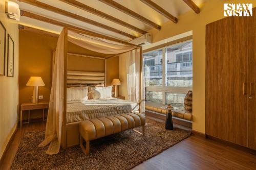a bedroom with a canopy bed and a window at StayVista at La Casa Oberoi with Lawn & Mountain View in Bhīm Tāl